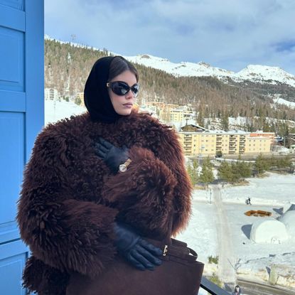 Kaia Gerber wearing a fuzzy brown coat with black leather gloves and black sunglasses