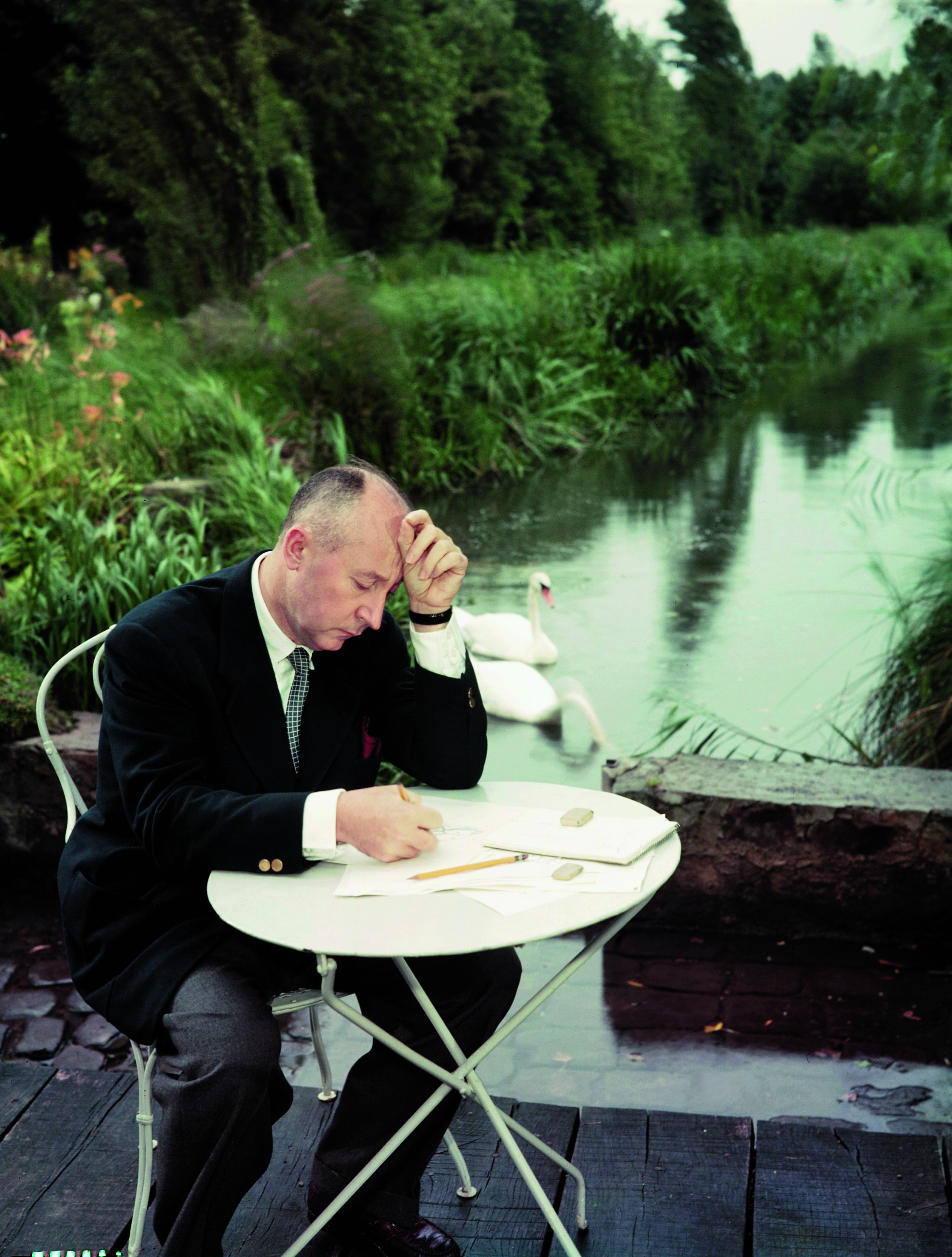 Christian Dior sketching at a white table in his own garden
