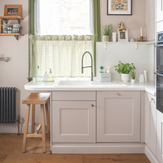 Small kitchen, with pink cupboards and ginham window cover.