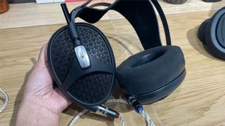 Meze Audio Empyrean II open-back headphones in hand showing both sides of earcup