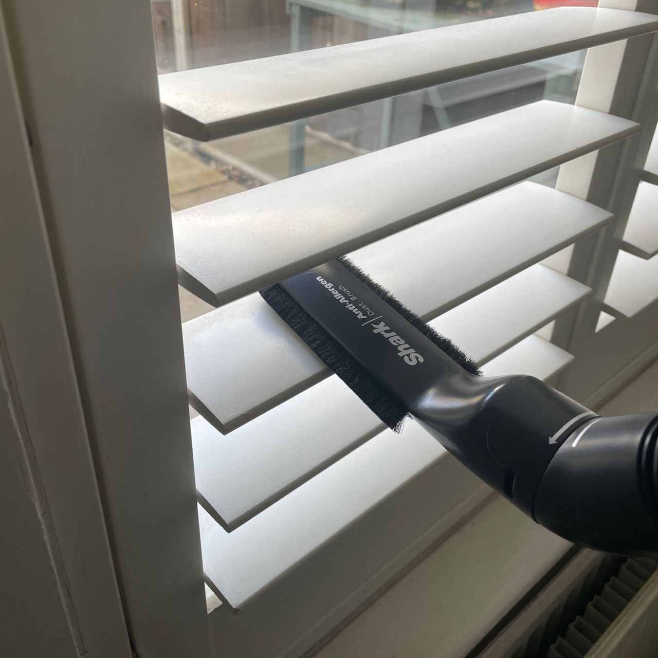 Shark Stratos Cordless Vacuum dusting tool being used to clean shutter blinds