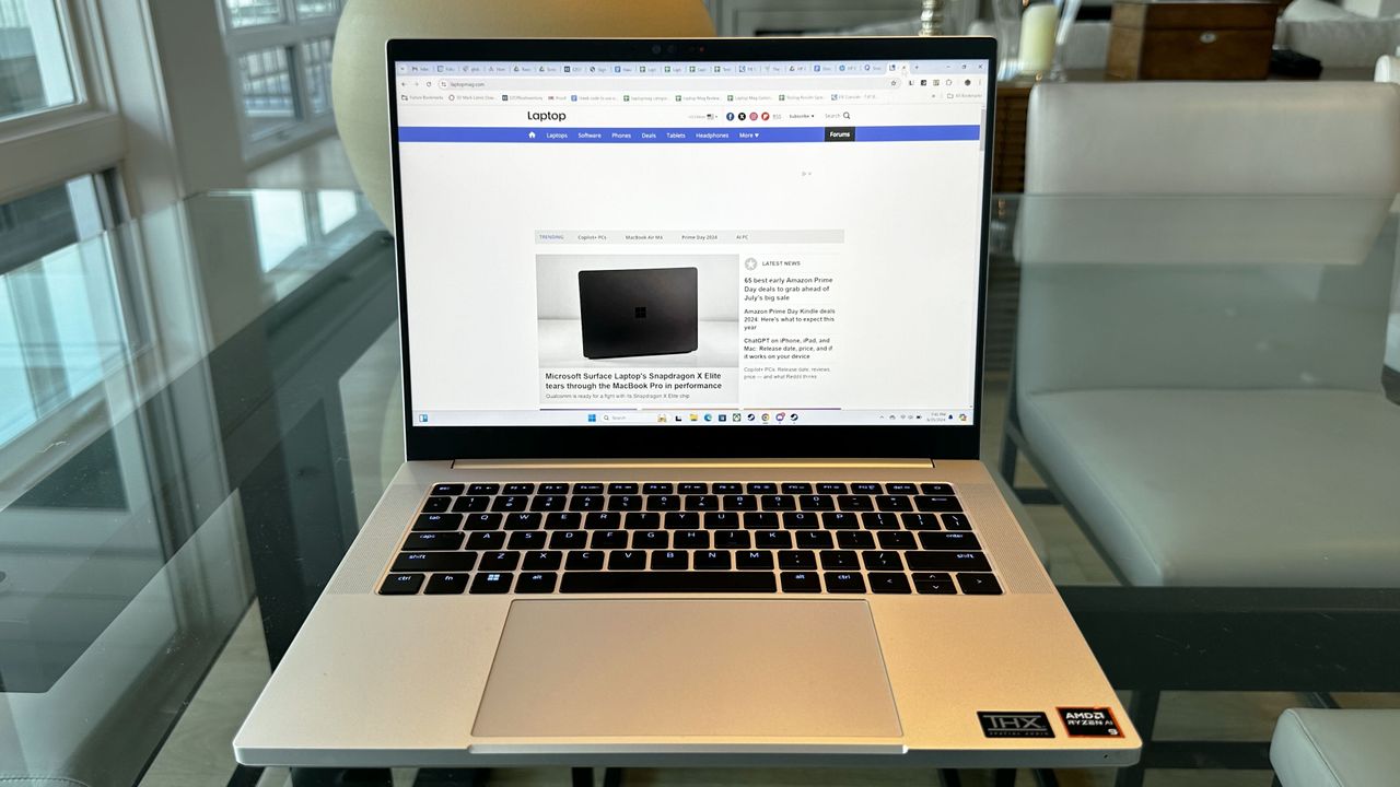 Razer Blade 14 (early 2024) open on a glass desk showing Laptop Mag on the display.