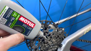 Close up of person's hand applying bike lube to chain
