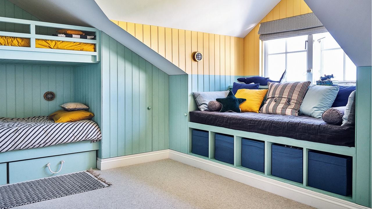 attic room with light blue walls, window seating with storage underneath and grey carpet