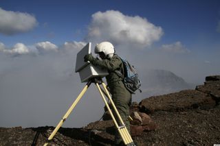 Geologist changing the data card from the time-lapse camera on the north rim of Pu'u 'O'o cone.