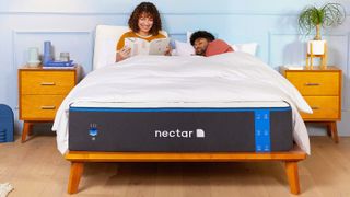 A couple sit in bed while relaxing on the Nectar Mattress