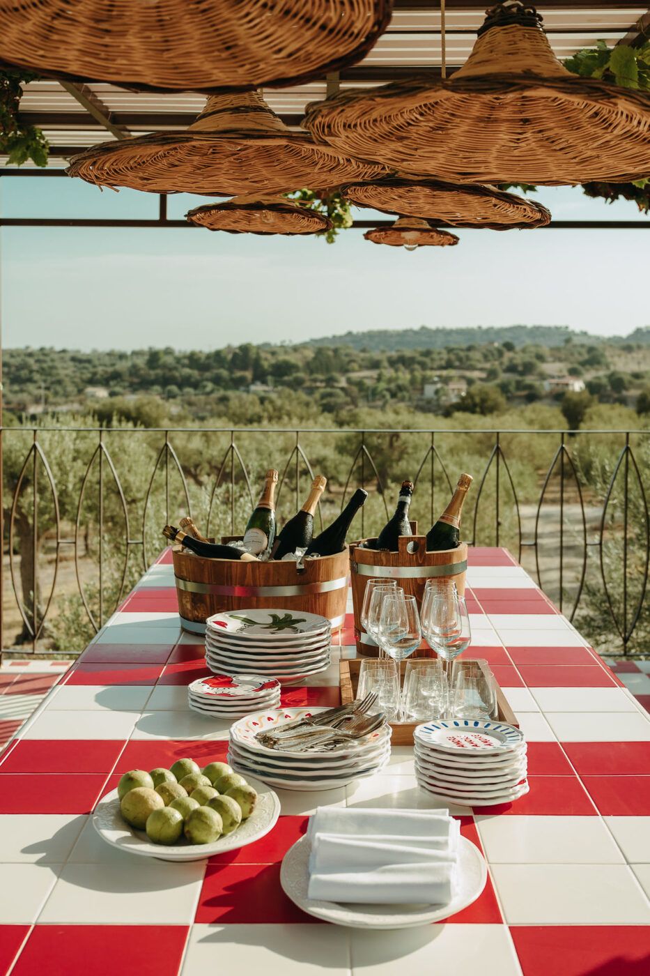 A sprawling Sicilian hotel rises within a dense, sun-kissed olive grove, boasting red and white tiling, rattan roofs, and white-washed walls.