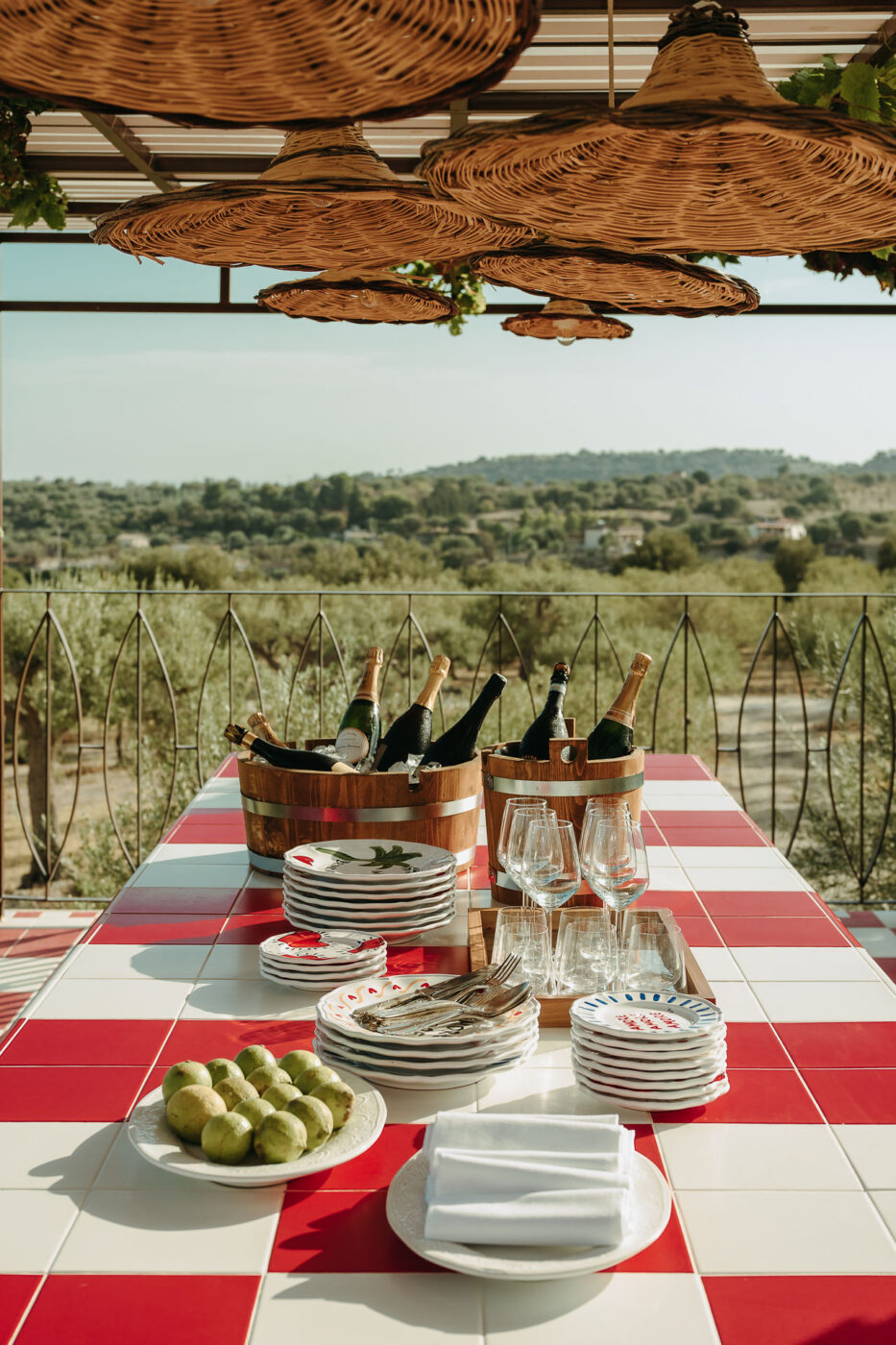 A sprawling Sicilian hotel rises within a dense, sun-kissed olive grove, boasting red and white tiling, rattan roofs, and white-washed walls.