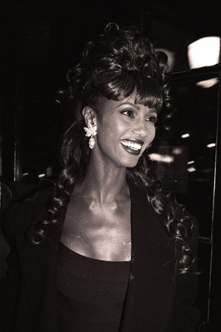 1980s Fashion: Iman wearing a dress and blazer attending an event
