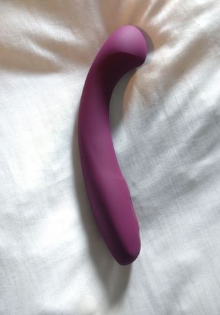 Dame Arc image by Ness Cooper A dark pink Dame Arc vibrator on a white crumpled bedsheet