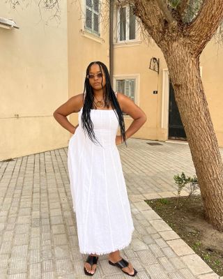 Woman wearing a white linen dress with thong sandals.