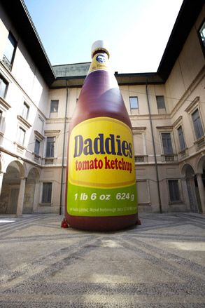 A huge inflatable of 'Daddies tomato ketchup' is set in a courtyard.