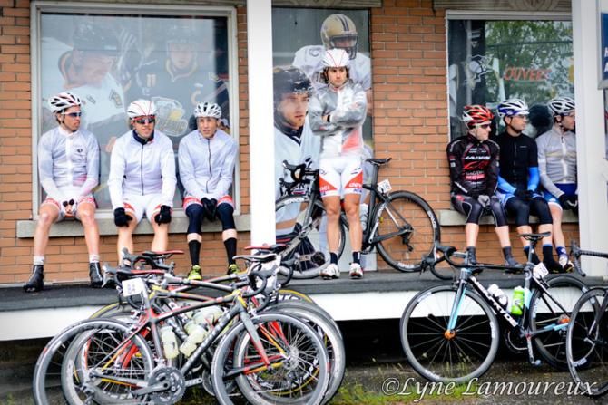Riders shelter from the rain before the start