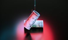 Two rolled-up one-hundred-dollar bills under a red light, with one caught on a fishing hook to indicate a scam.