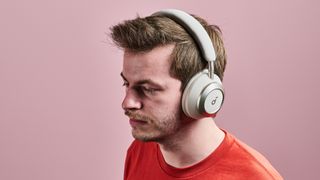 A man wearing the Anker Soundcore Space One Pro in front of a pink wall