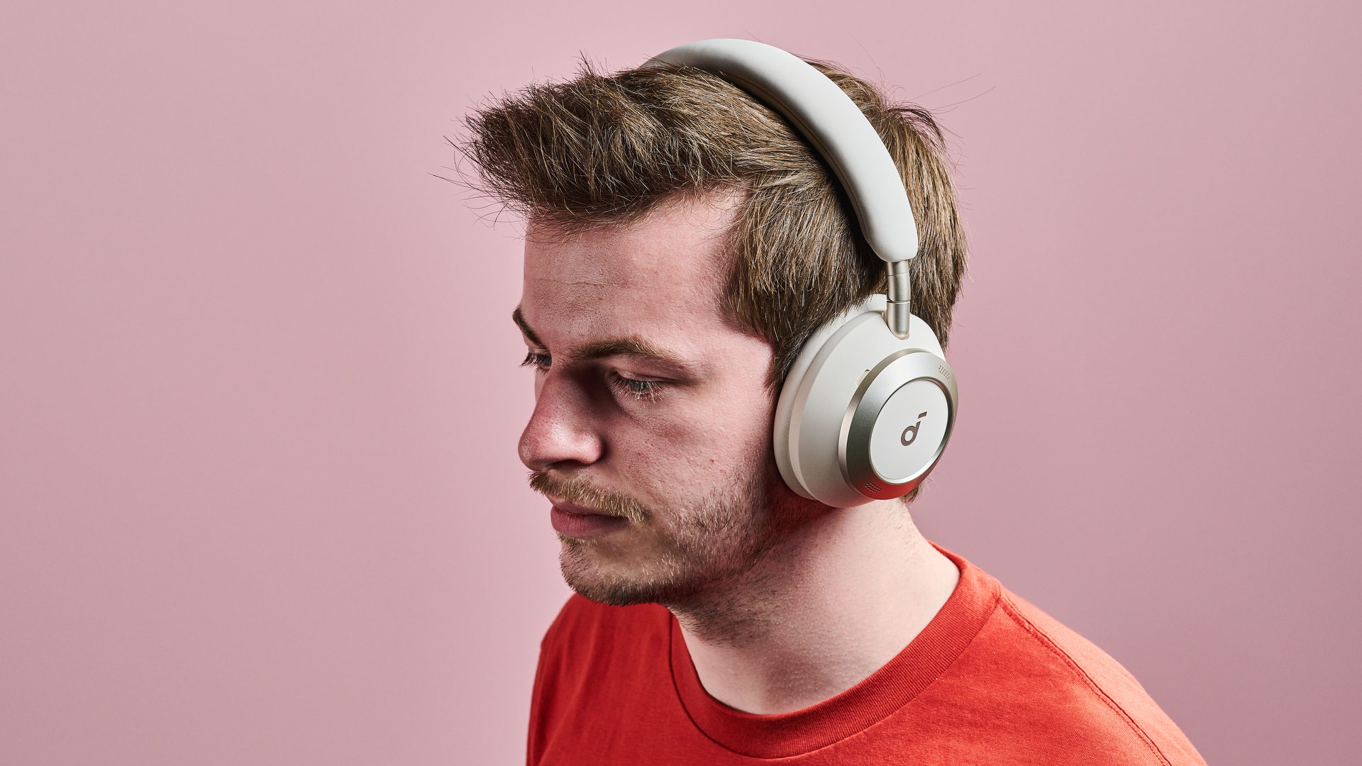 A man wearing the Anker Soundcore Space One Pro in front of a pink wall