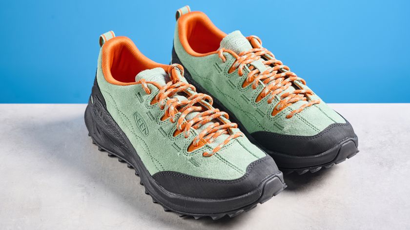 the keen jasper zionic hiking shoes in green/gold colorway photographed against a blue tom's guide background and a stone floor, showing the lug sole and the leather upper with orange laces