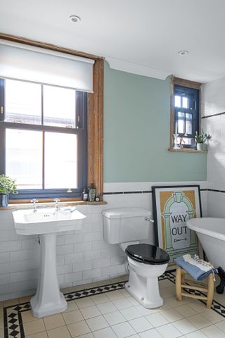Bathroom with white metro tiles and pastel green paint, traditional sanitaryware and 'Way out' print