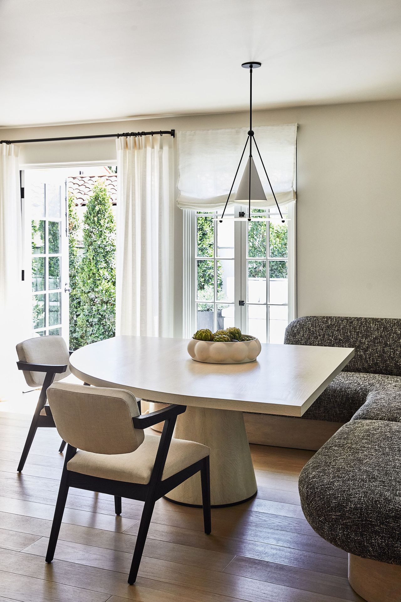 A curved banquette couch in a dining area of a neutral house renovation