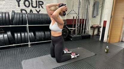 Woman doing the dumbbell halo exercise in a gym