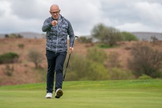 A golfer celebrates holing a putt