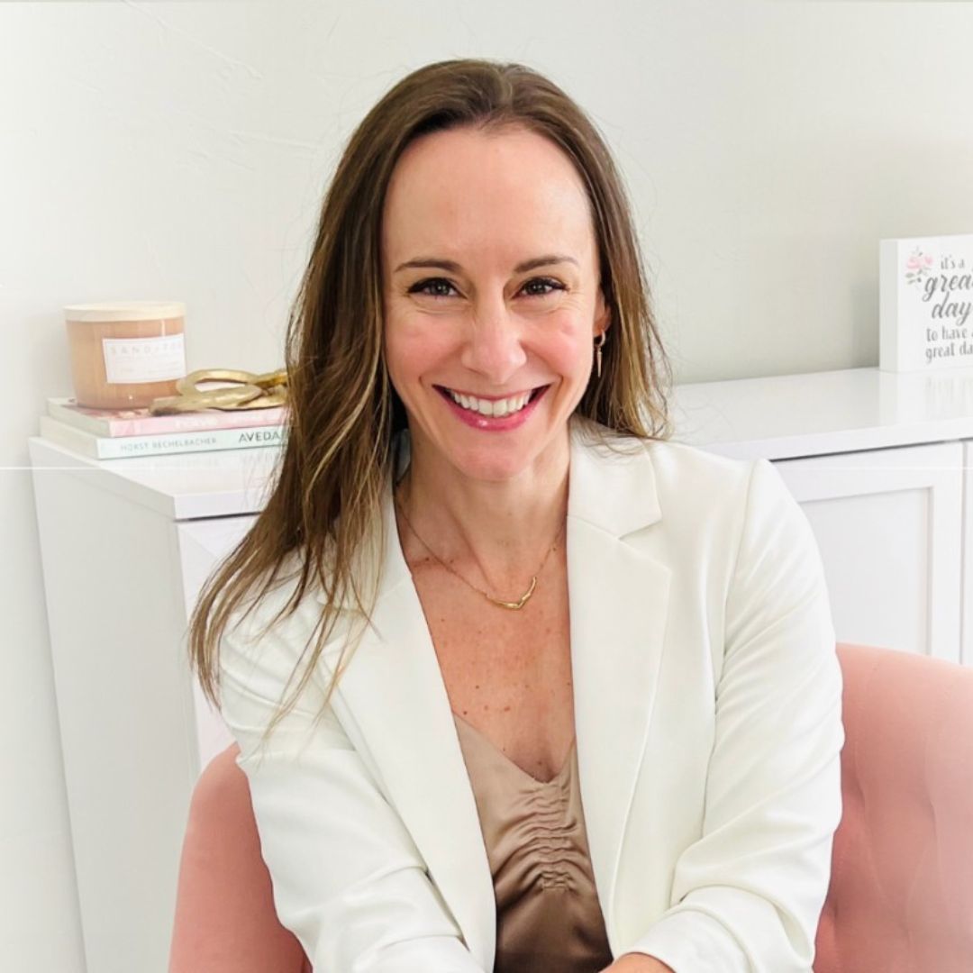 A headshot of Dr Nicole Maholy wearing a white jacket and smiling at the camera