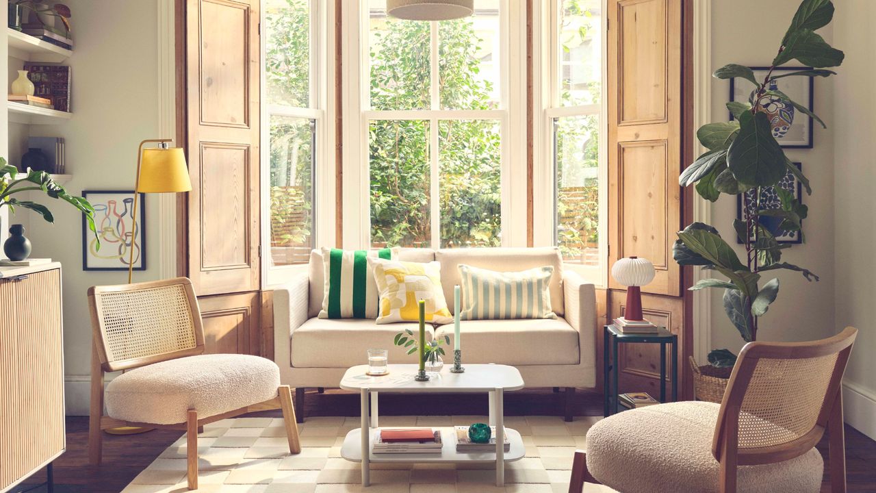 Light-filled living room with large bay windows at the back and boucle chairs on either side of the cream sofa