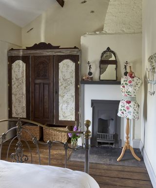 Bedroom with fireplace and antique wardrobe and dress making mankin decorated in floral fabric