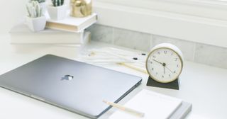 Laptop computer, desktop clock and notepad.