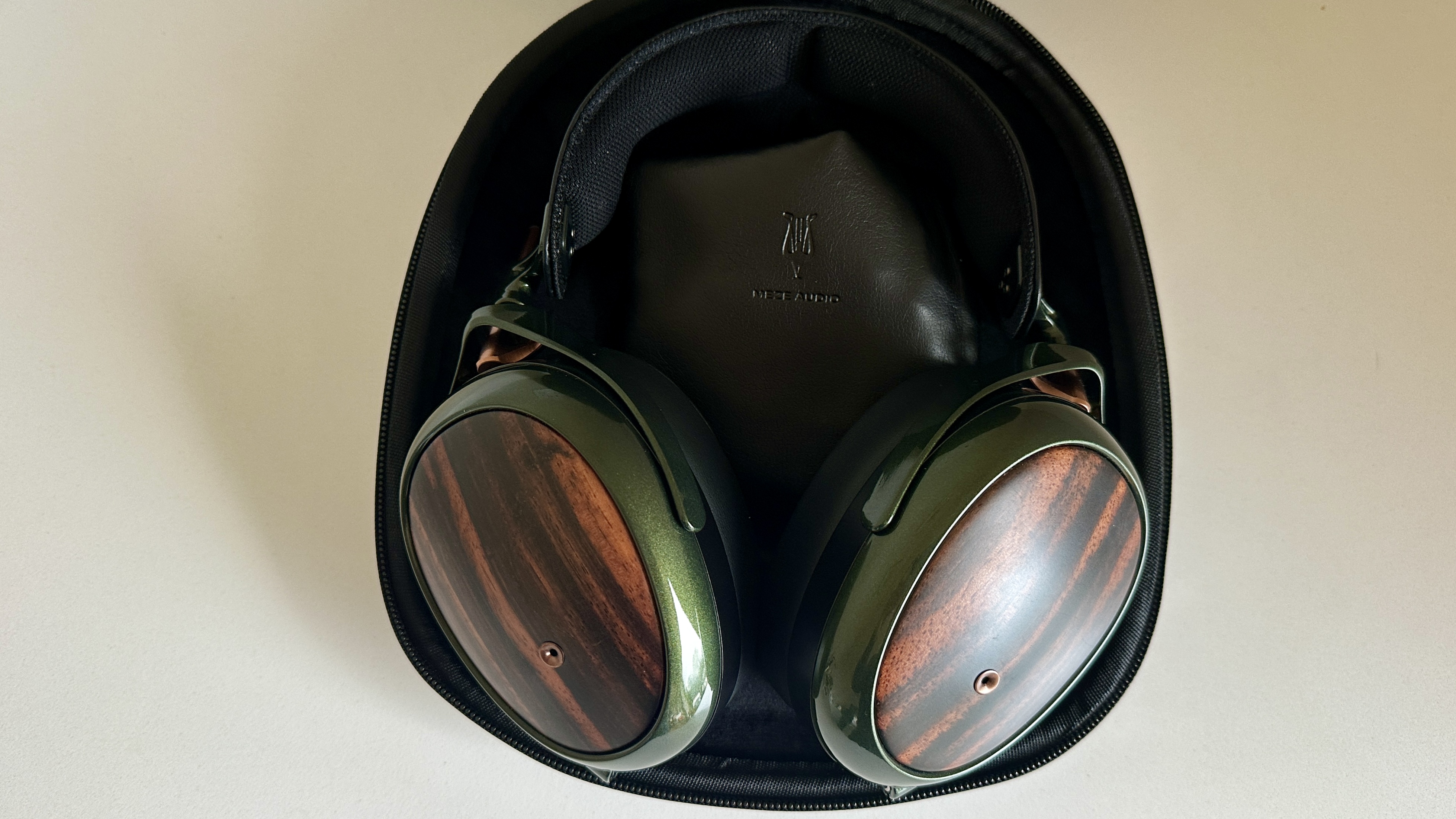 Meze Audio Strada headphones with wooden ear cups, in close-up and with their case and cables visible, on a white table