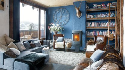 living room in French chalet home with blue walls and stove lit