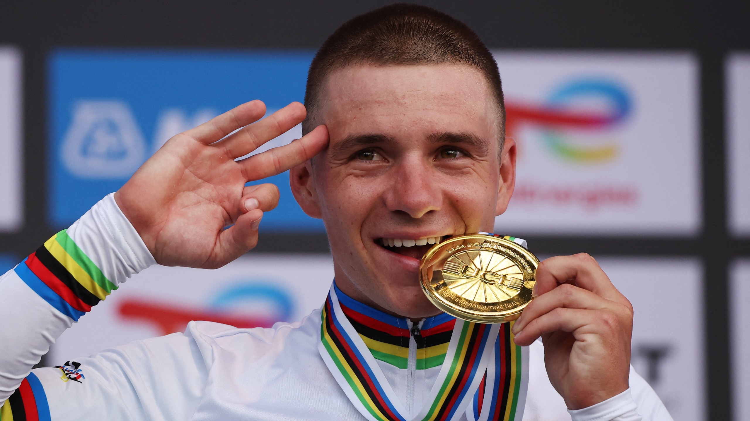 Gold medallist Belgian rider Remco Evenepoel bites on his medal on the podium following the men's Elite Individual Time Trial cycling event during the UCI 2025 Road World Championships