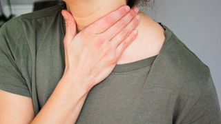 woman touching her neck with one hand