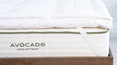 Avocado mattress topper on a white Avocado mattress and a dark wood bedframe