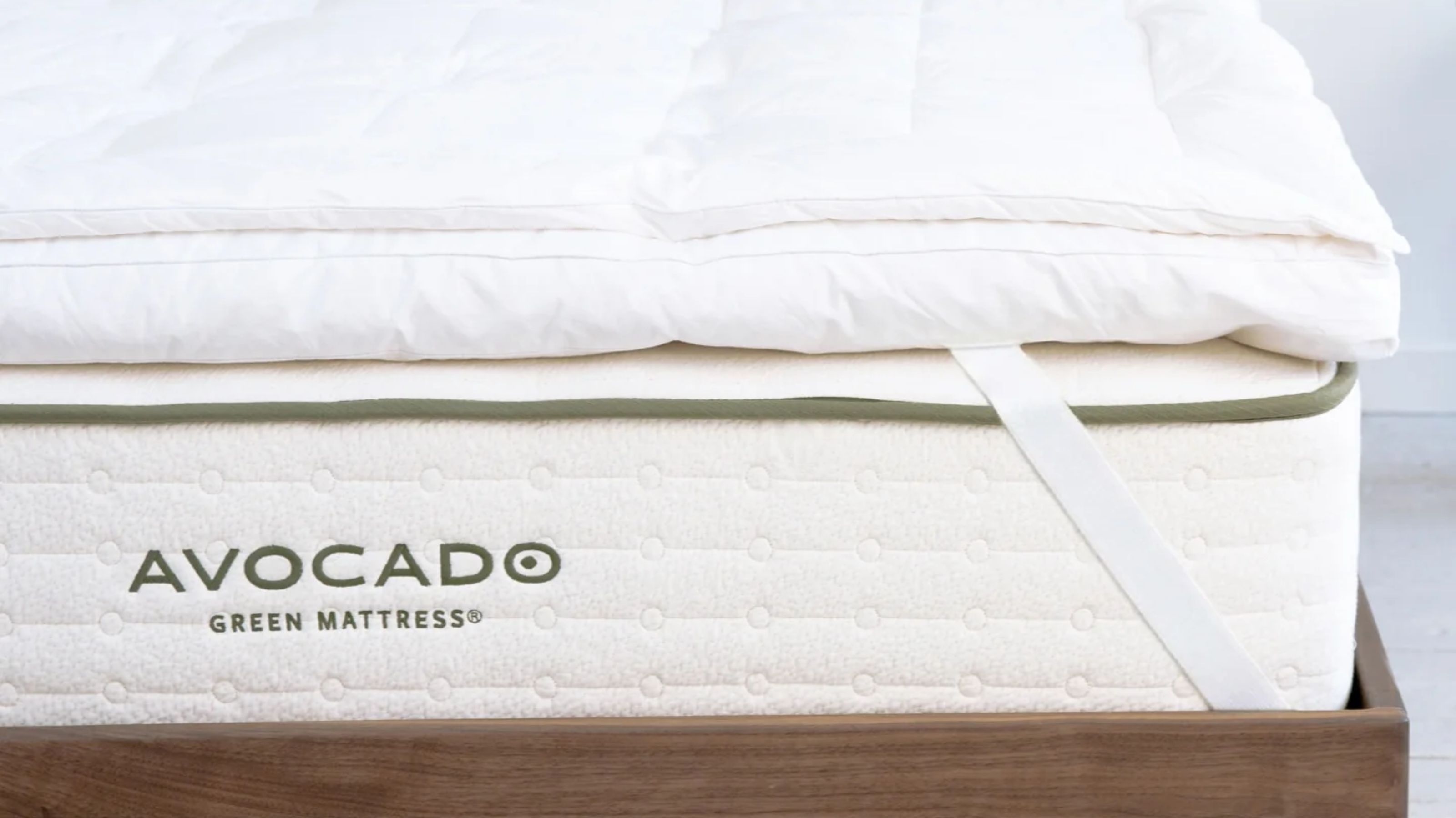 Avocado mattress topper on a white Avocado mattress and a dark wood bedframe