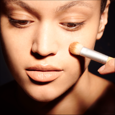 Woman applying powder makeup with brush 