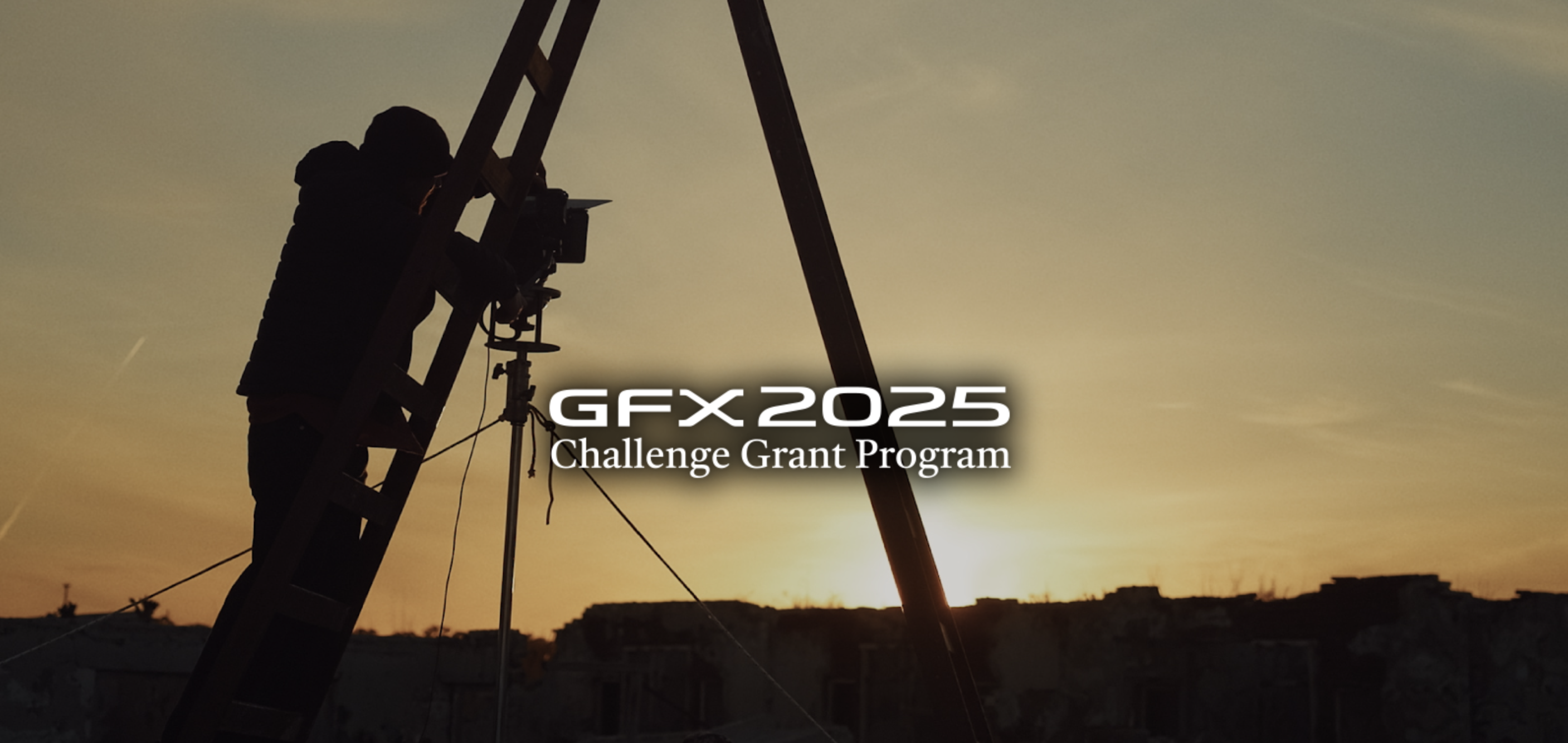 A silhouetted person adjusts a camera on a ladder against a sunset backdrop, promoting the GFX2025 Challenge Grant Program