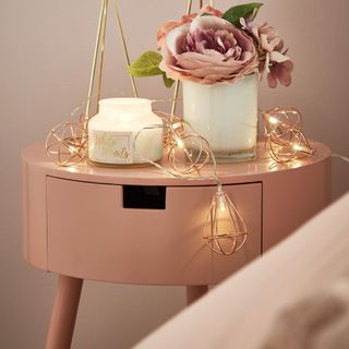 bedroom with pink bedside table with flower in vase