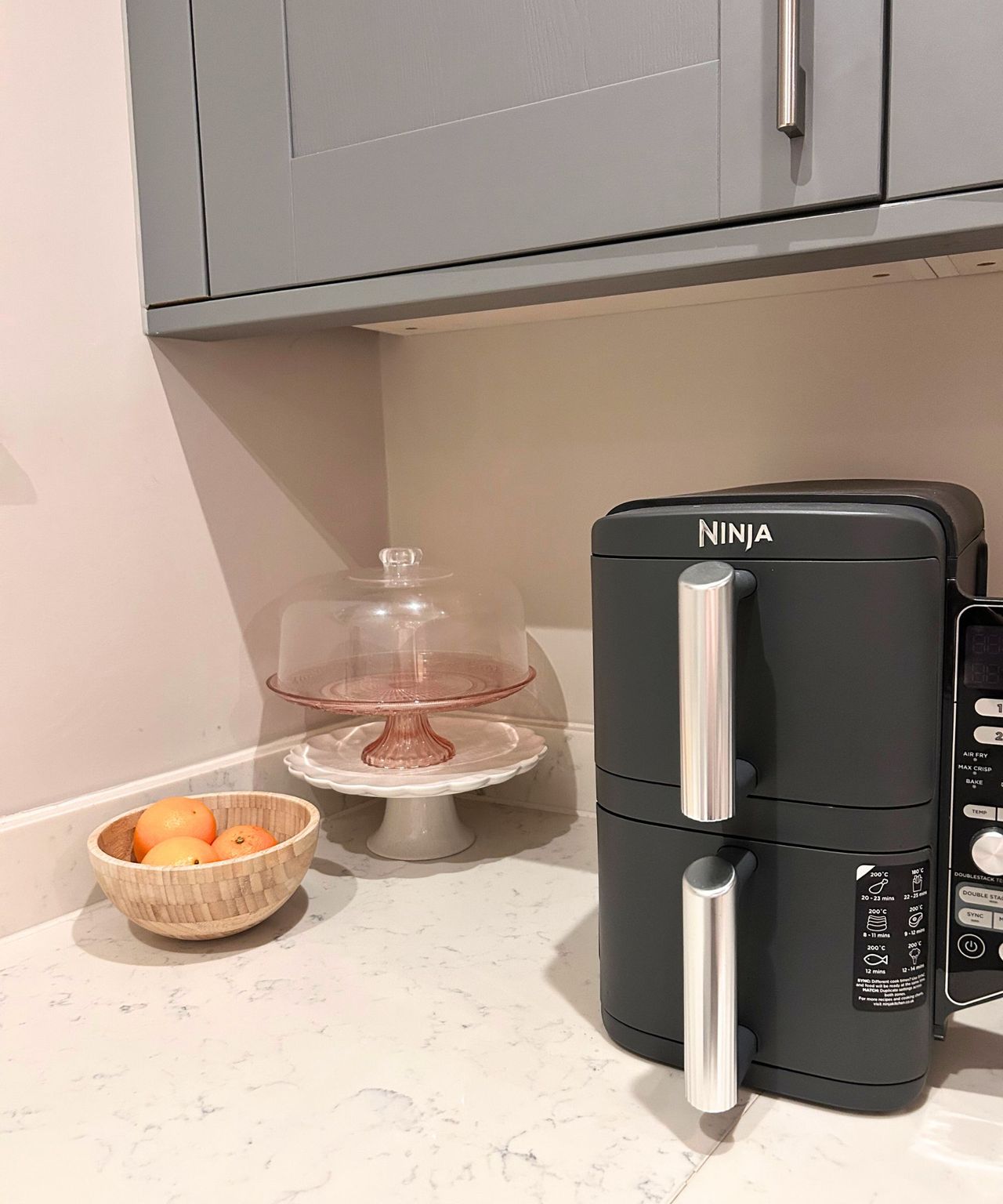A tidy kitchen corner with air fryer, oranges and cake stands
