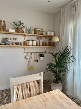 wooden shelving unit with food containers and hanging rails by a table in a dining room