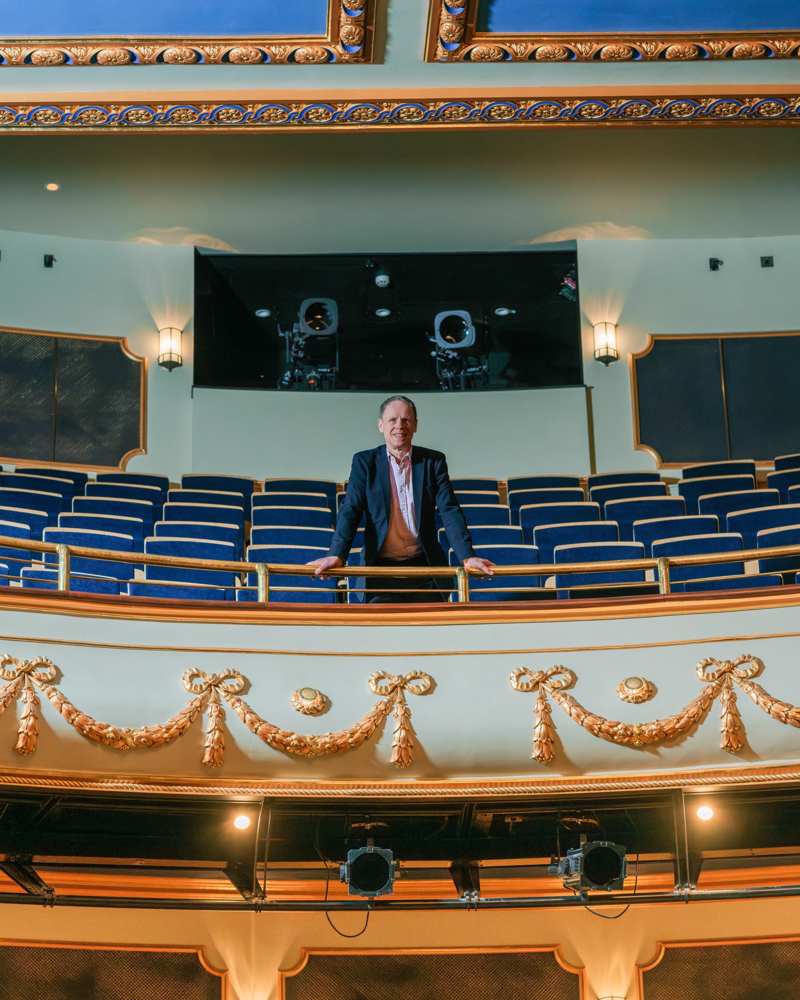 Sebastian Warrack stands at the top of the circle row of seats, looking down into the camera.