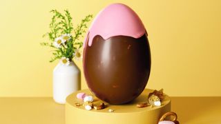 Chocolate egg with pink top in front of a yellow background