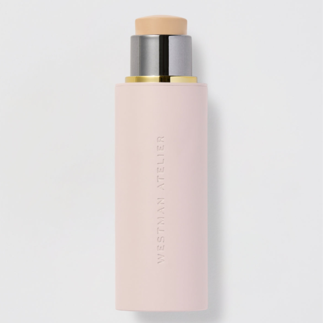 A product shot of the Westman Atelier Vital Skin Foundation Stick, which is housed in a pastel pink tube and pictured on a grey background