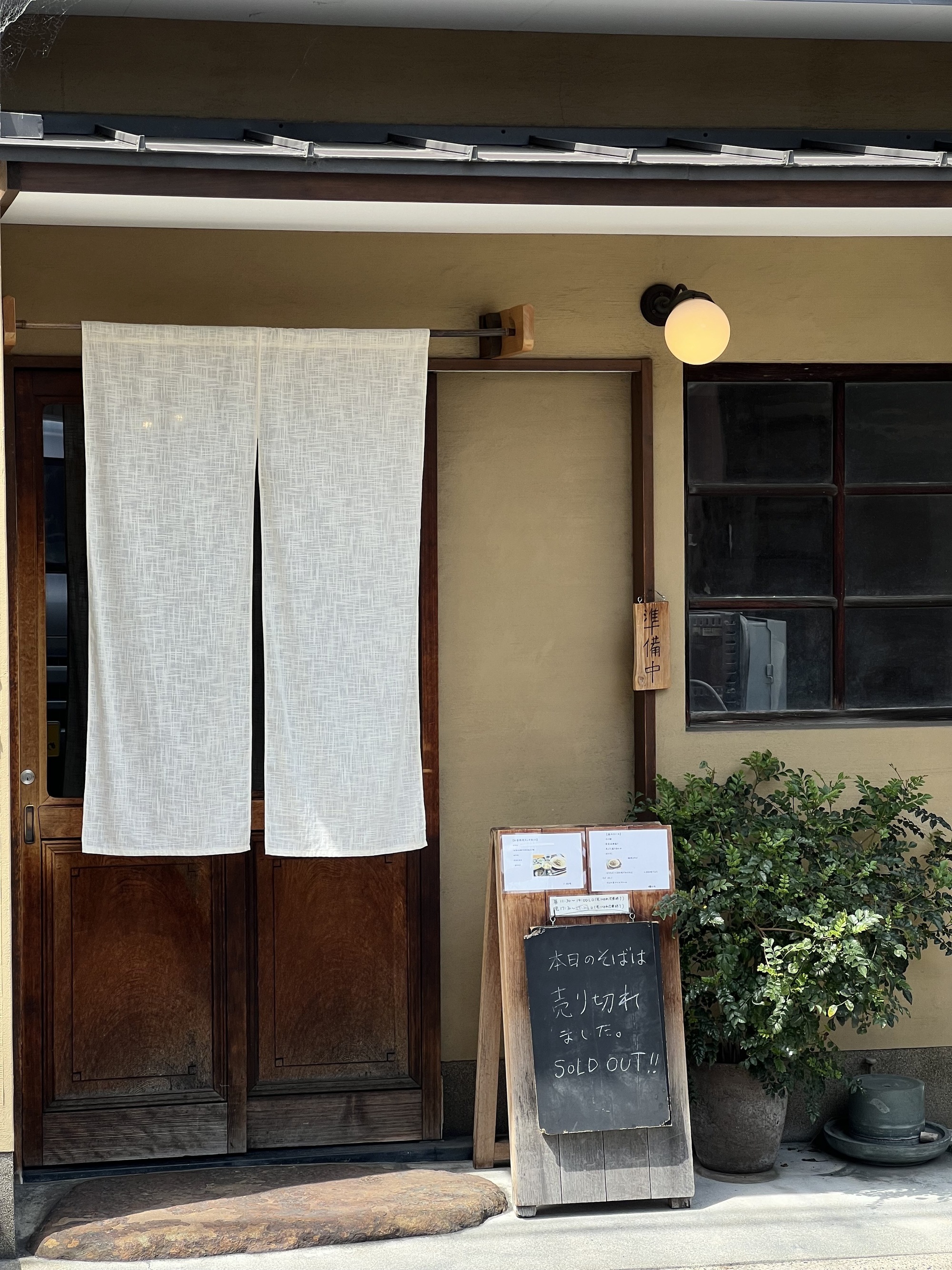Image of white linen noren curtains in front of the exterior door of a building in Japan.
