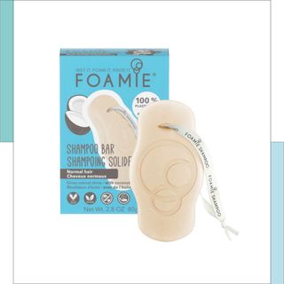 Foamie shampoo bar with ribbon hanging off standing in front of the product box