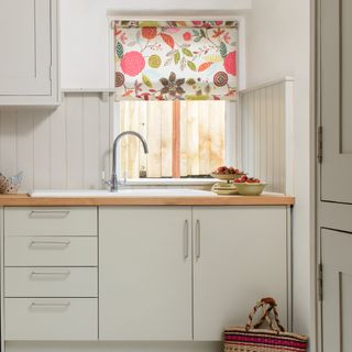A cream kitchen with floral-print roller blinds