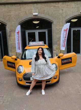 Scarlett Moffatt outside her unique driving school and a yellow car