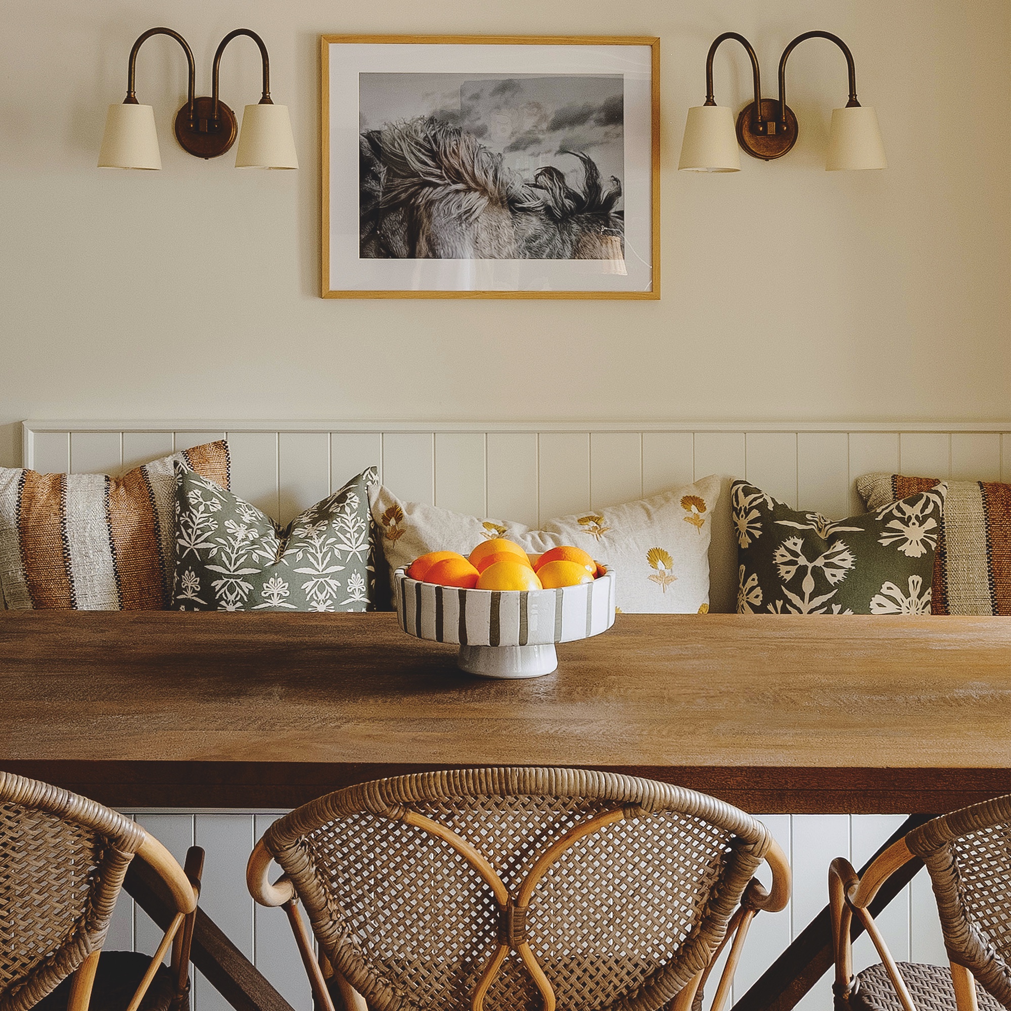 dining room with wooden built in bench seating and long wooden table with wall lights behind