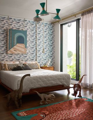 boys teen bedroom with blue wave wallpaper, retro turquoise pendant, artwork, dinosaurs, animal rug, hardwood floor