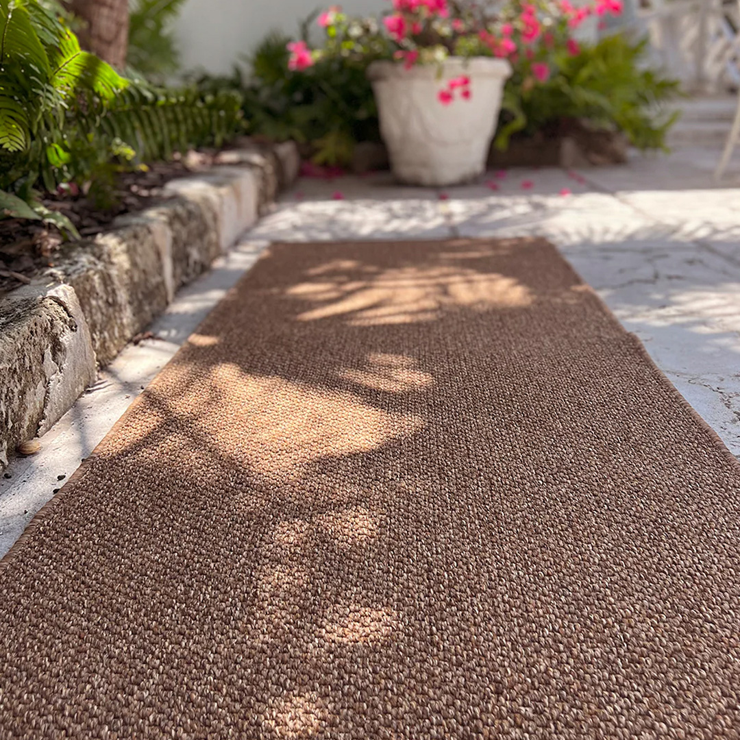 Brown woven outdoor runner shown on a patio in the spring